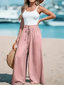 Detail of casual pink high-waisted wide-leg trousers styled in a sunny beach setting