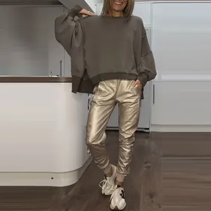Close-up of women's side slit sweatshirt and metallic gold jogger pants fashion set