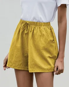 Primer plano detallado de pantalones cortos de lino amarillos con cordón y bolsillos laterales
