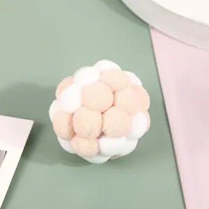 Close-up detail of soft plush pom-pom cat toy ball in soft pink and white colors