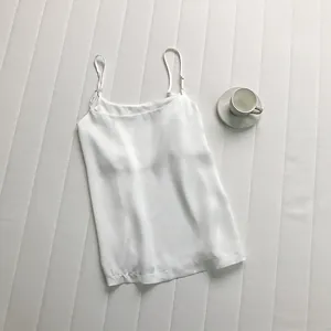 Dettaglio di un elegante canotta in raso bianco con spalline sottili