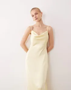 Full view of elegant pale yellow satin cowl neck slip dress with a slim fit and glossy finish