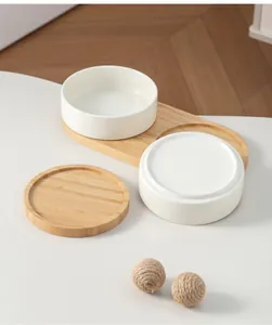 Dettaglio delle ciotole in ceramica bianca per animali con vassoio e base in bambù.