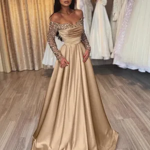 Elegant champagne gold sequined evening gown with long sleeves and floor-length satin skirt.