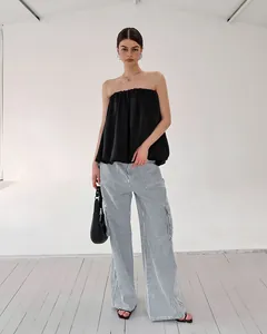 Modèle portant un haut bustier noir en satin avec un pantalon rayé chic