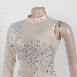 Primer plano de un vestido ajustado de malla color carne con brillantes detalles de pedrería.