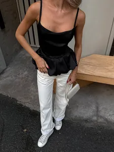 Elegant woman wearing a black satin peplum camisole with white jeans outdoors