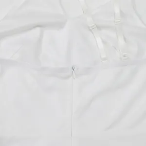 Close-up detail of back invisible zipper and adjustable straps on white jumpsuit.