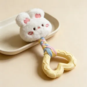 Close-up detail of plush rabbit dog toy with heart-shaped rubber teether and braided rope.