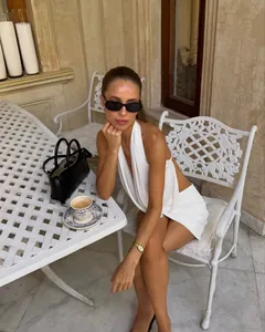 Σικ λευκό σατέν σετ με εξώπλατη μπλούζα και φούστα σε μοντέλο σε ευρωπαϊκό καφέ.