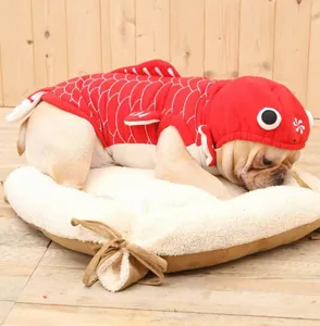 Dettaglio di un cane che indossa un costume da pesce rosso 3D su un letto beige per animali