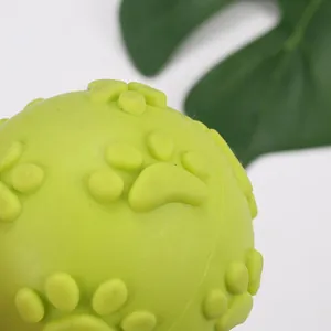 Detailed macro view showing the textured paw print pattern on the green TPR dog toy ball