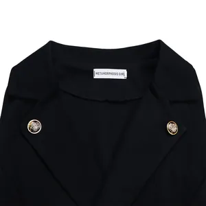 Close-up of black blazer jumpsuit collar with gold crest buttons and brand label