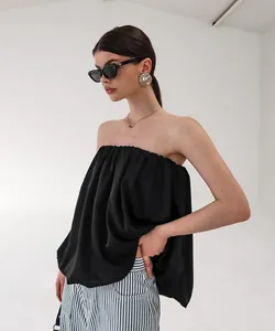 Haut bustier élégant en satin noir avec ourlet évasé dans un décor de studio épuré