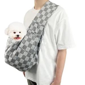 Model draagt een grijs geblokte draagzak voor huisdieren met een kleine witte hond