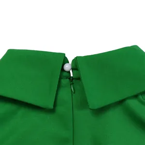 Close-up detail of green dress collar with white pearl button and hidden back zipper