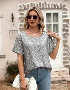 Haut à paillettes argentées assorti à un jean bleu et une pochette blanche élégante