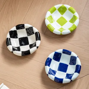 Three stylish checkerboard ceramic pet bowls in blue green and black on wood floor