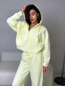 Full-body lifestyle view of a pale yellow two-piece zip-up hoodie and sweatpants set