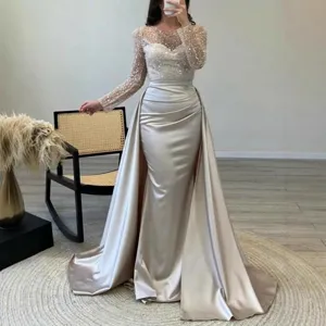 Elegant champagne sequined long-sleeve evening gown with satin draped mermaid overskirt.