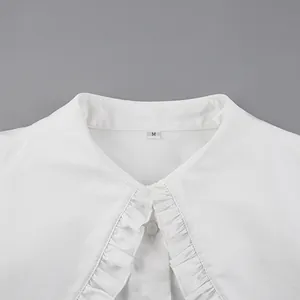 Detailed close-up view of a white doll collar shirt with elegant ruffles and size tag M