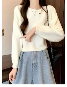 Close-up detail of soft white knit sweater featuring a unique diagonal pleated neckline.
