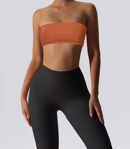 Detail of a seamless orange bandeau sports bra paired with high-waisted black yoga leggings.