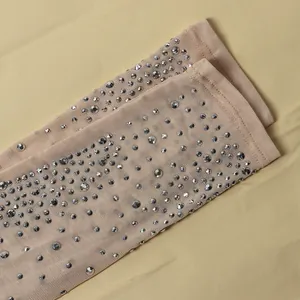 Dettaglio ravvicinato di strass argentati su tessuto a rete beige semi-trasparente