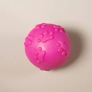 Pink rubber dog toy ball with raised paw print texture for teething and play