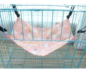 Detail of pink cat hammock with polar bear pattern hanging in a blue wire cage