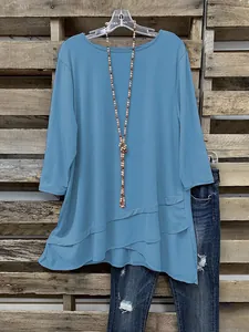 Detailweergave van casual blauwe tuniek met onregelmatige zoom en driekwart mouwen
