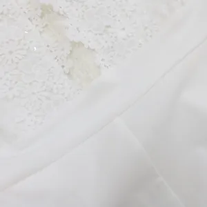 Vista detallada de la textura de encaje floral blanco y la tela lisa de este mono