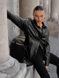 Chic black faux leather shirt jacket for women worn by a model in an urban setting