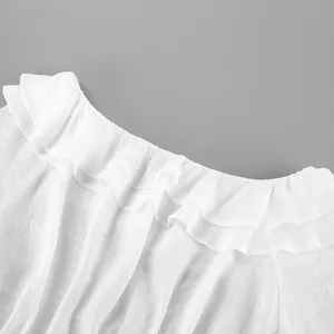 Détail de l'élégant décolleté à volants aux épaules dénudées d'une blouse d'été blanche