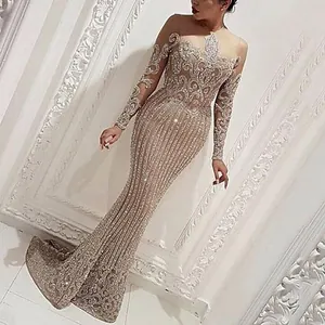 Close-up detail of elegant gold sequined mermaid evening gown with long sleeves.