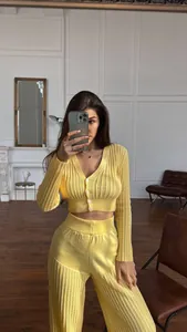 Close-up of yellow hollow knit set featuring high waist trousers and cardigan