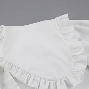 Detail of white doll collar shirt with ruffle edges and pure cotton texture.
