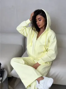 Detail view of a pale yellow zip-up hooded sweatshirt and matching sweatpants on a model.