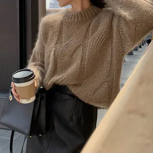 Detailed lifestyle shot of a woman wearing a chunky cable knit sweater and leather skirt