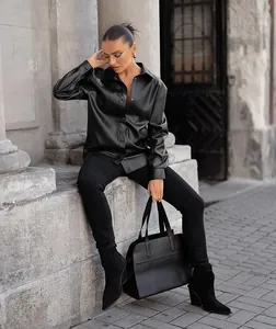 Model wearing black PU leather shirt jacket sitting on stone steps in an outdoor city setting