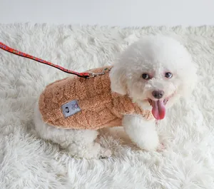 Detailed view of brown fleece dog vest with leash attachment on a white Bichon Frise