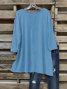 Detail van een blauw T-shirt met een onregelmatige zoom en 3/4-mouwen.