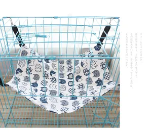Adjustable cat hammock with blue animal patterns hanging in a blue wire cage