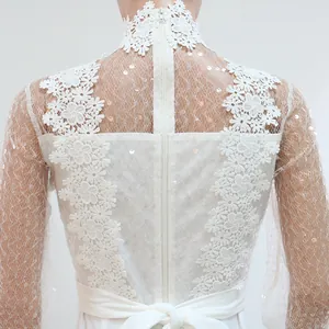 Primer plano de top de encaje blanco con cuello alto, lentejuelas y malla transparente