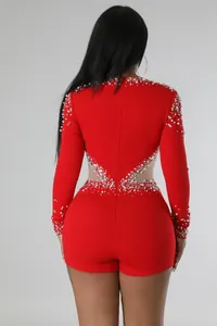 Vista posteriore di una tutina rossa a maniche lunghe con perle, strass e rete velata.
