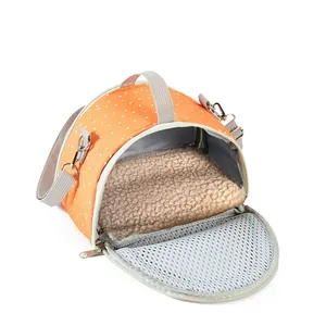 Detail view of a portable orange polka dot small pet carrier with soft plush interior mat.