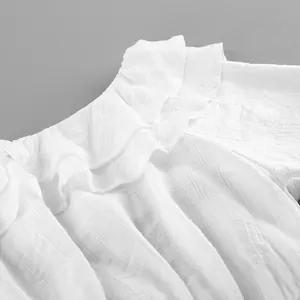 Détail rapproché d'un chemisier blanc élégant à volants et épaules dénudées en tissu
