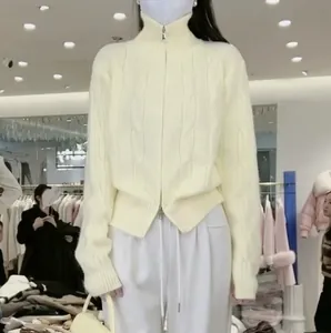Detail of cream cable-knit high-neck cardigan with a functional double zipper design