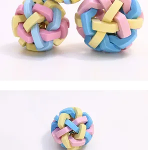 Close-up detail of a durable TPR dog toy ball with colorful interwoven design and bell