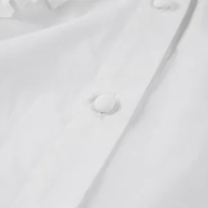 Macro detail view of a white pure cotton shirt featuring elegant fabric-covered buttons